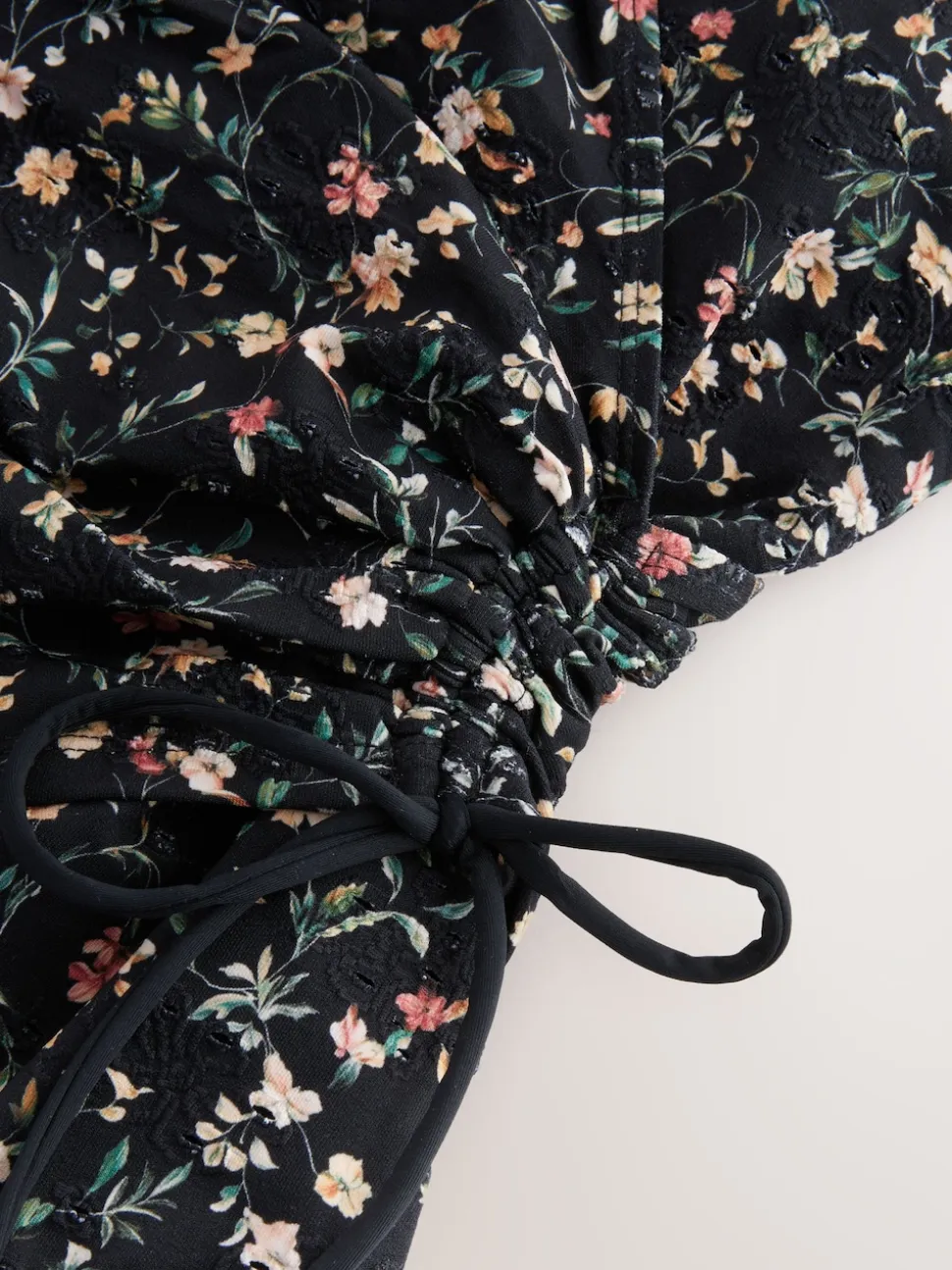 Zwart met broderie en fijne print - Badpak met vormgevende zijrimpeling en buikcorrectie